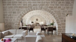 A spacious living area with a stone wall and an arched doorway leading to a dining area.