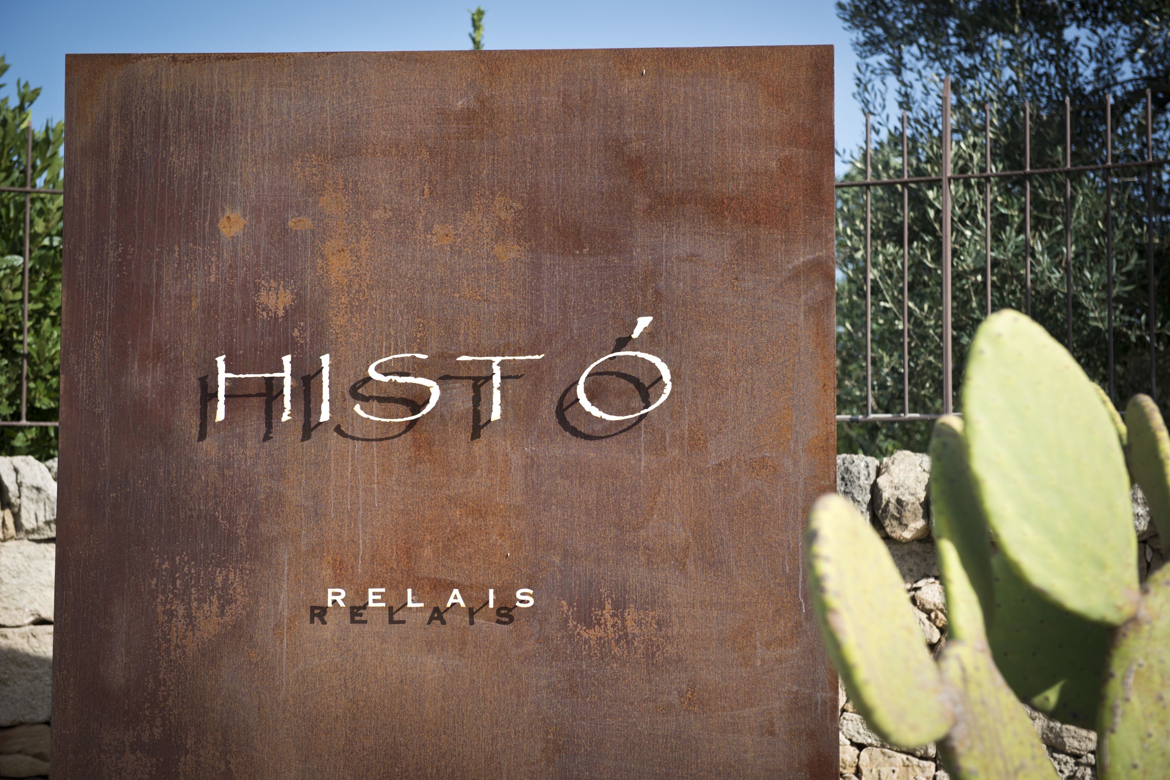 Un letrero con el texto 'HISTO' y 'RELAIS' sobre una superficie metálica oxidada.
