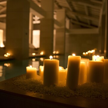 A row of lit candles on a reflective surface, likely in a hotel lobby or similar public space.
