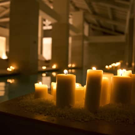 A row of lit candles on a reflective surface, likely in a hotel lobby or similar public space.