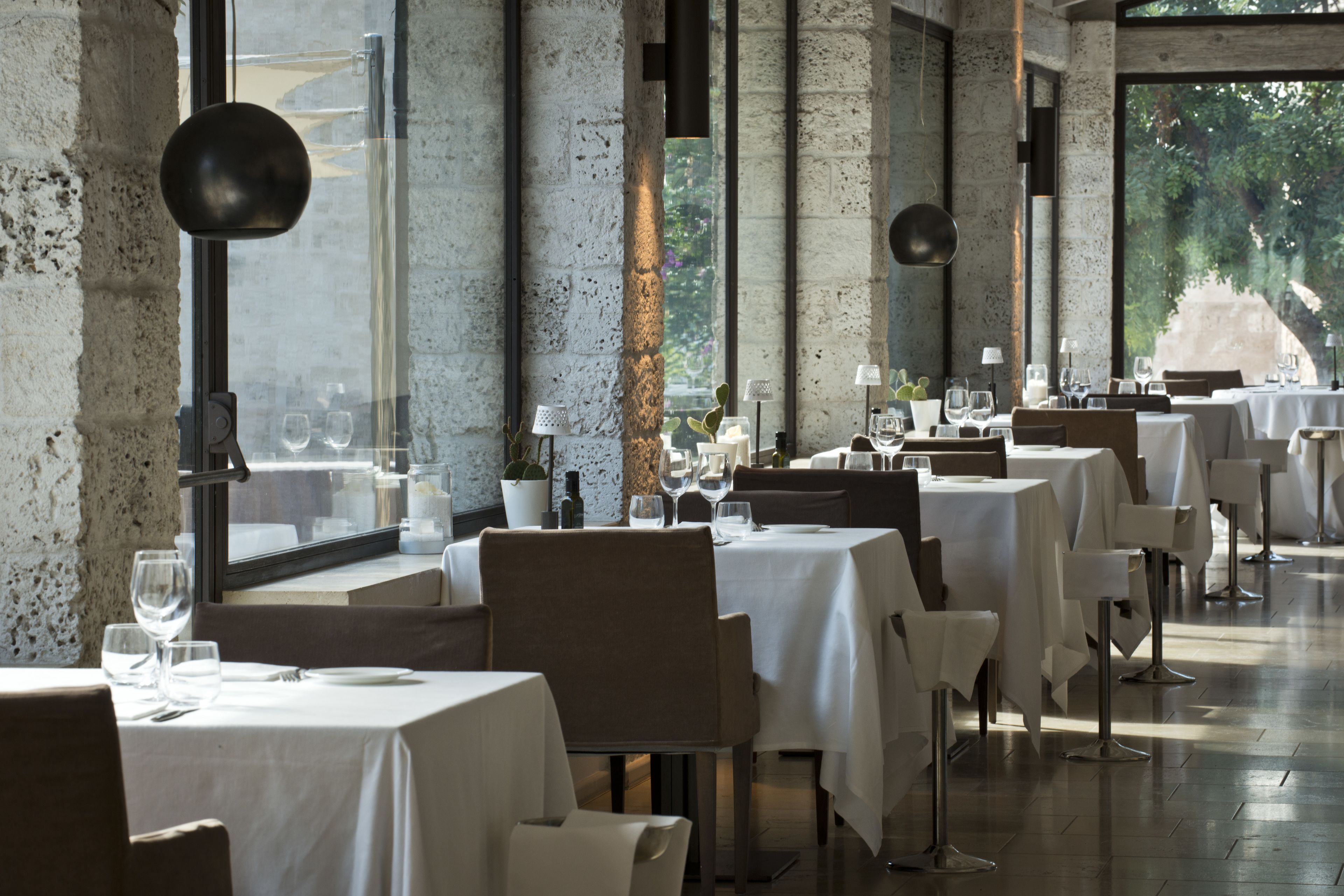 A restaurant with white tablecloths, modern chairs, and large windows.