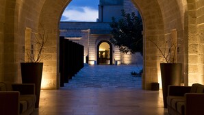 An arched corridor with a stone floor, leading to a building entrance.
