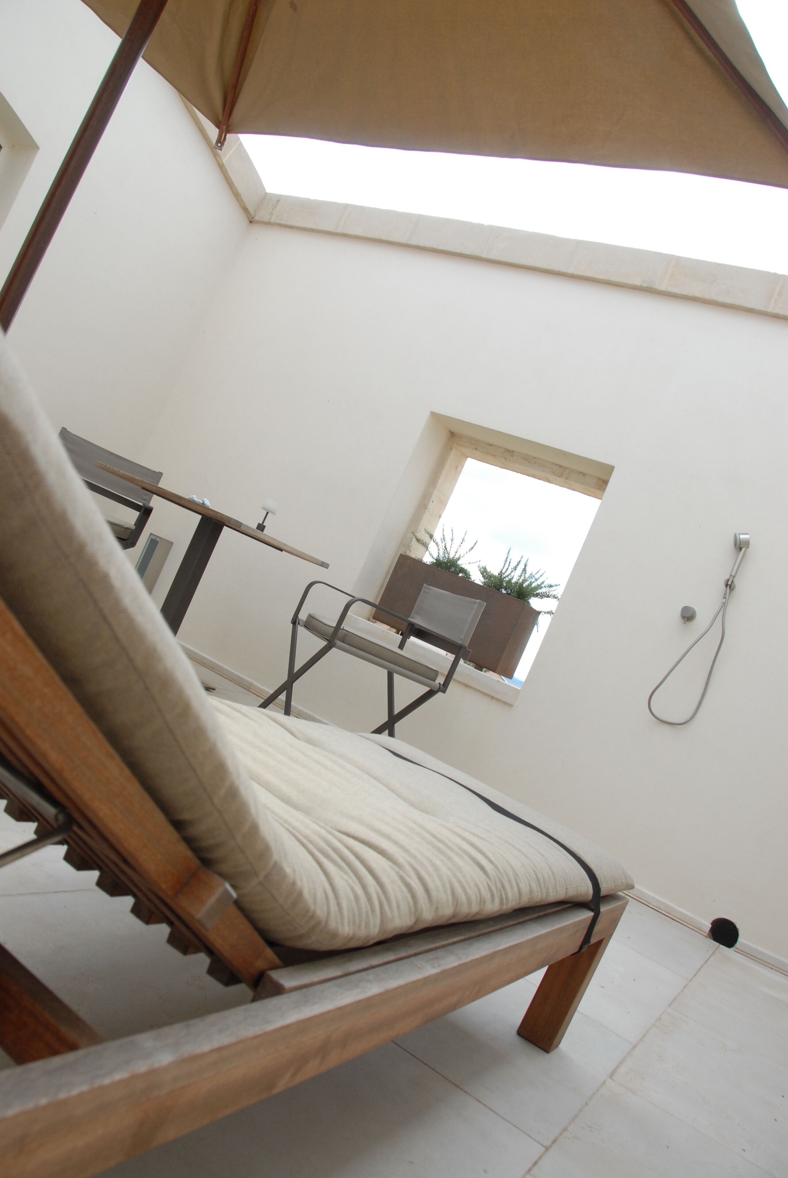 Una habitación con cama, ventana, ducha y una pequeña mesa.