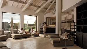 A spacious living room with multiple sofas, a coffee table, and a kitchen area with built-in shelves.