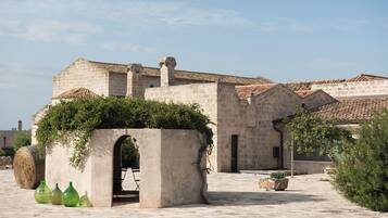 A courtyard with a stone building, a small archway, and potted plants.
