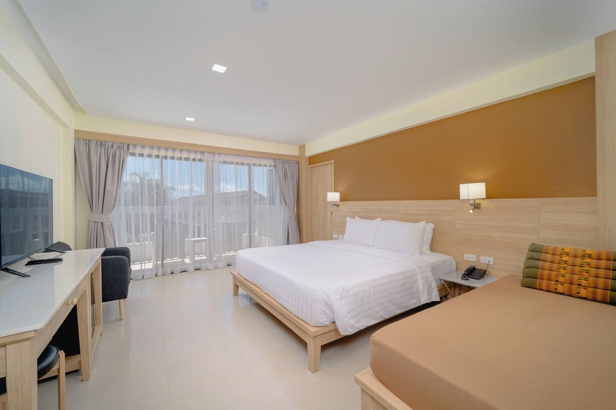 Una habitación de hotel con cama, mesita de noche, lámpara, escritorio con silla y televisor.