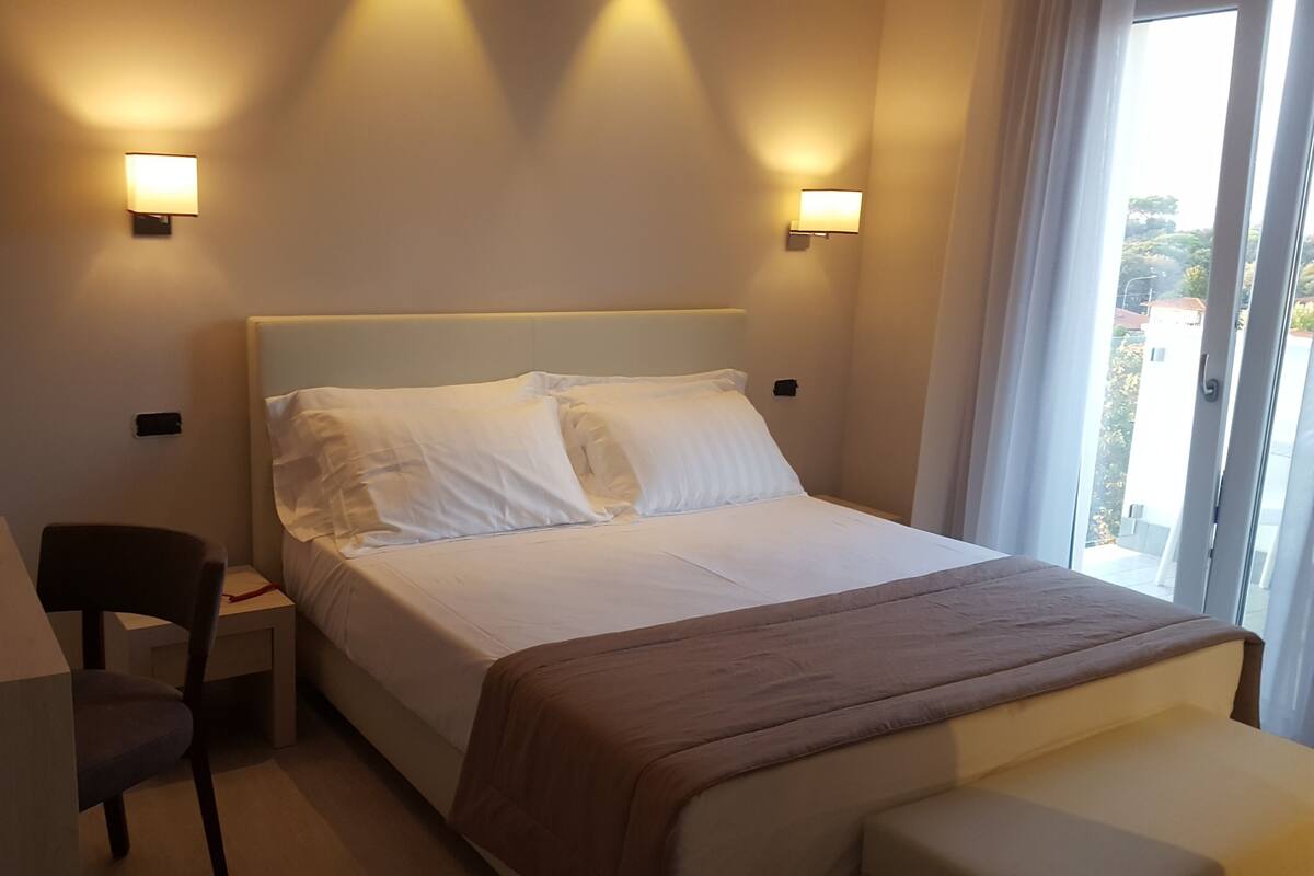 Ein Hotelzimmer mit Bett, Nachttischen, einem Sessel und zwei Wandleuchten.