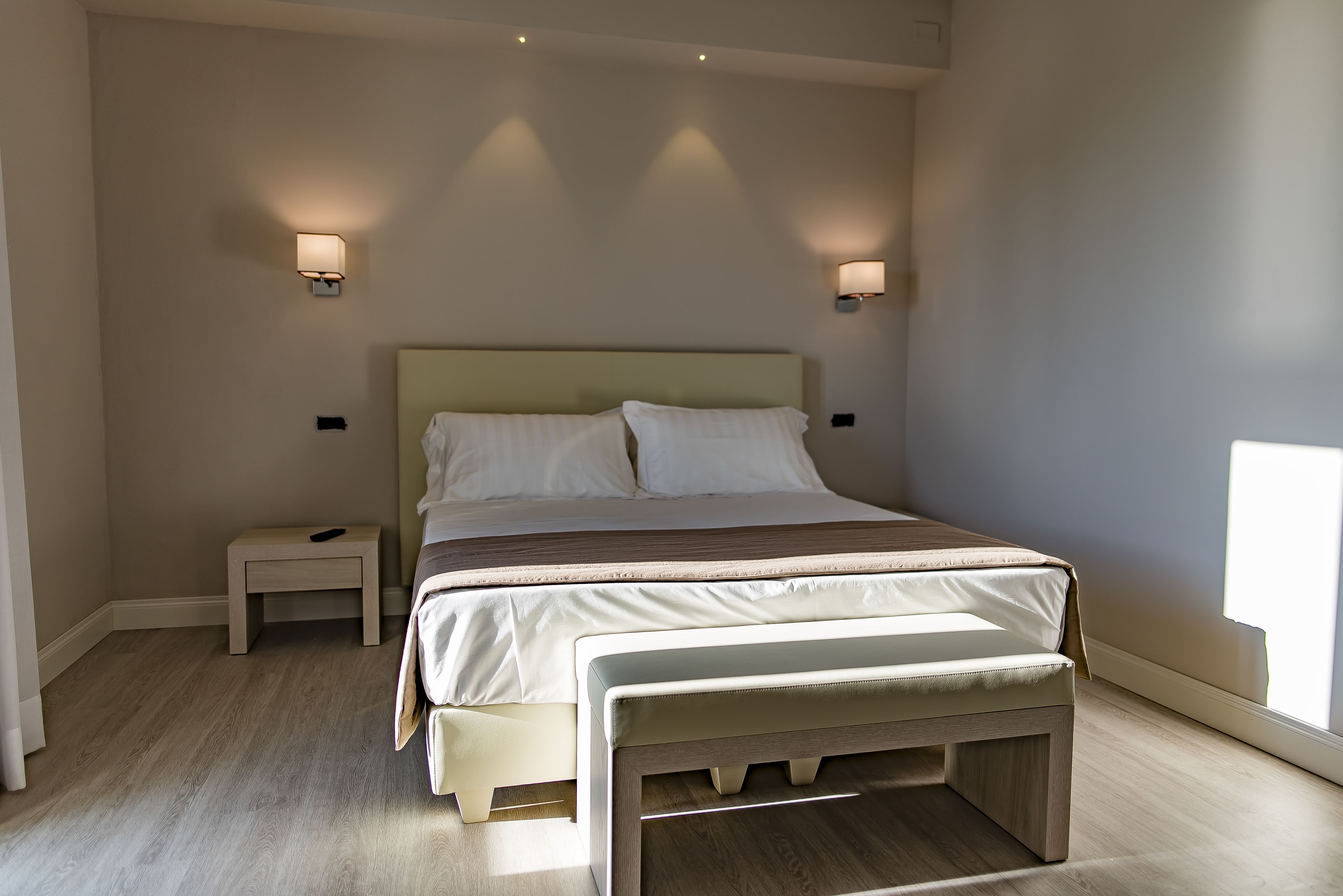 A bedroom with a bed, bedside tables, and a bench.