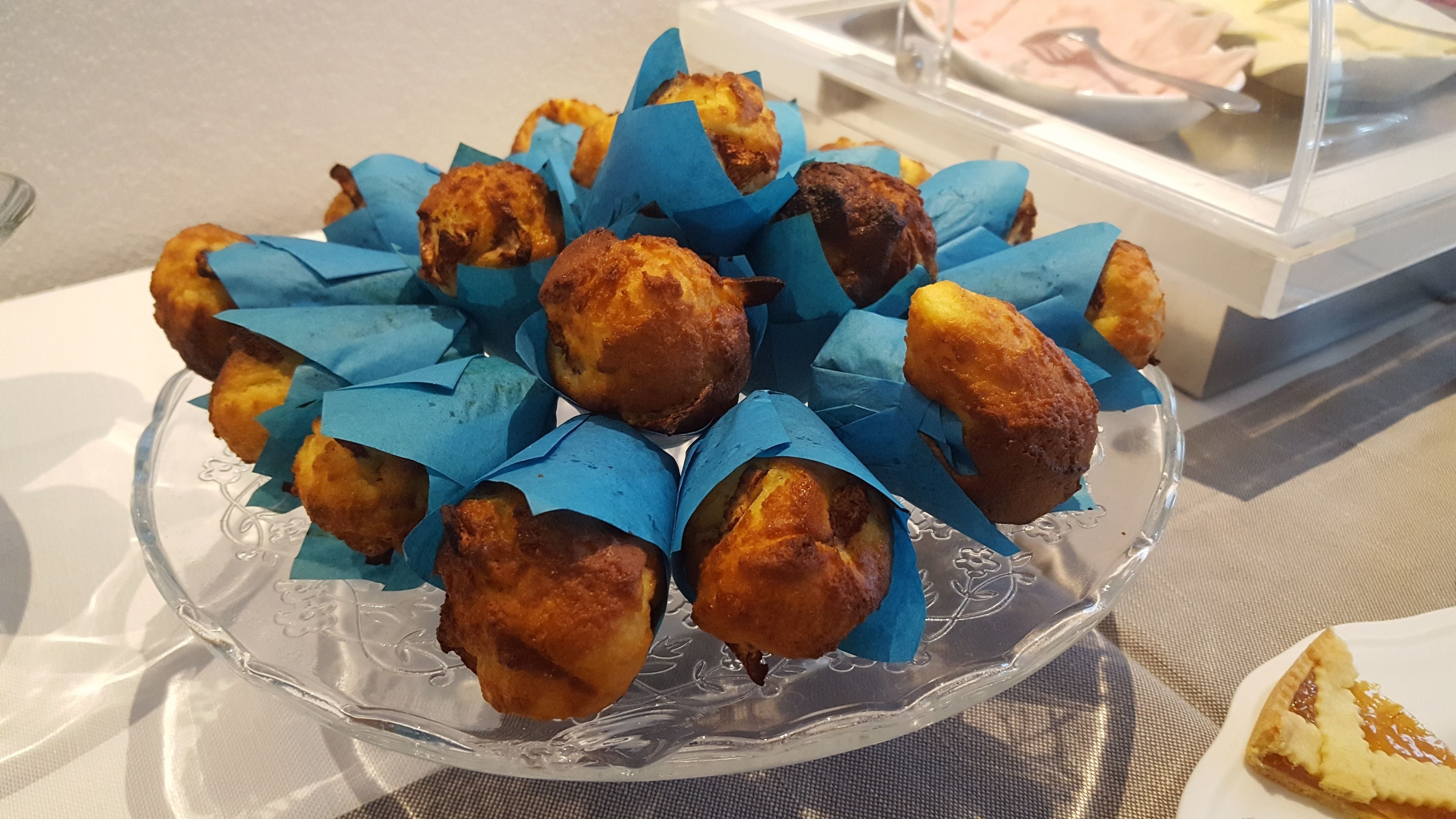 A glass plate with pastries wrapped in blue paper, placed on a table.