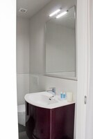 Un baño con un lavamanos blanco, tocador oscuro y un espejo grande.