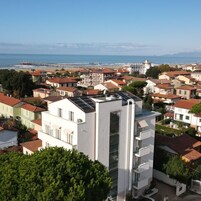 Zona residencial costera con edificios modernos y tradicionales, incluyendo un edificio blanco destacado con paneles solares.