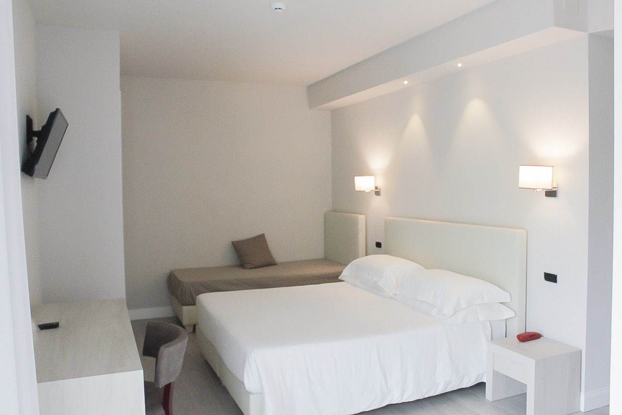 A hotel room with two beds, a bedside table, a chair, and a small desk.