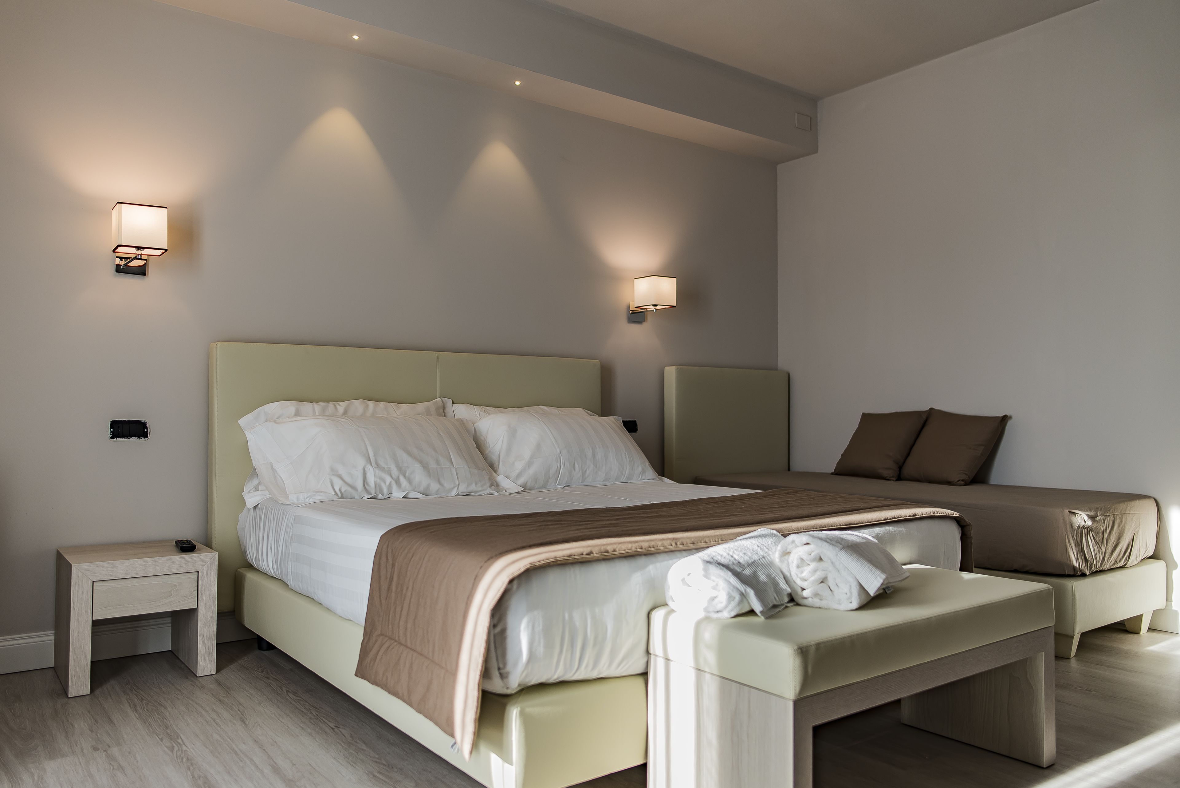 Ein modernes Schlafzimmer mit einem großen Bett, Nachttischen und Wandleuchten.