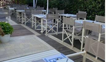 An outdoor patio with tables and chairs, some covered by umbrellas.