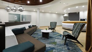 A modern hotel lobby with a curved ceiling, a reception desk, a sofa, a chair, and a coffee table. - SpringHill Suites by Marriott McAllen Convention Center (McAllen)
