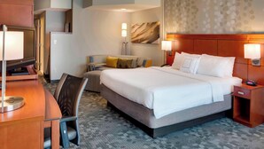 Une chambre d’hôtel avec un grand lit, un bureau, une chaise, une télévision et une lampe.