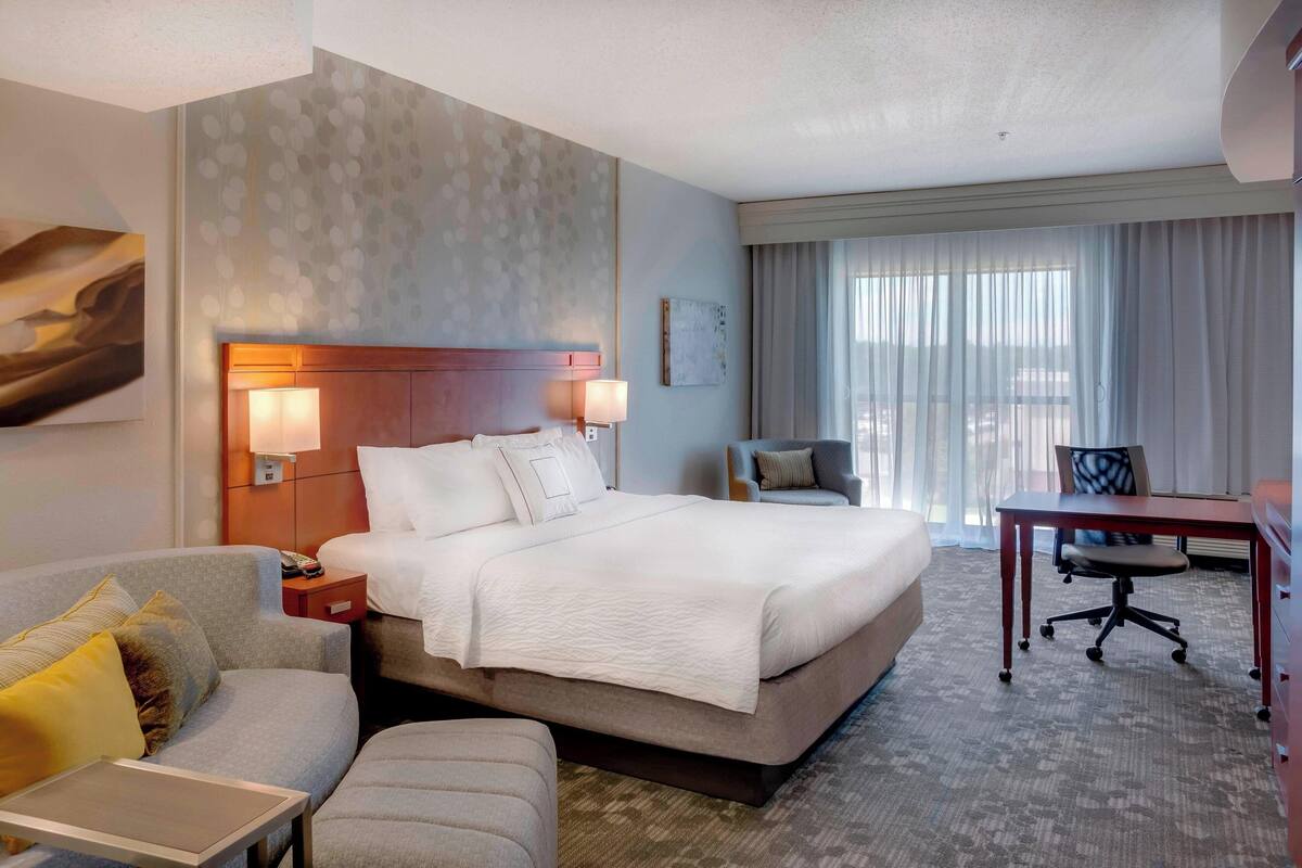 Ein Hotelzimmer mit einem großen Bett, einem Schreibtisch, einem Stuhl und einem Schlafsofa.