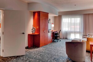 Habitación de hotel con escritorio, una silla, sofá y un amplio armario.