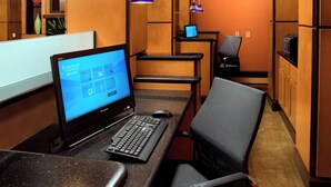A hotel room with a desk, computer, and seating area.