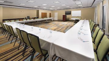 A conference room with a long table, chairs, water bottles, and a projector screen.