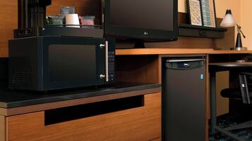 A compact kitchenette with a microwave, coffee maker, and refrigerator.