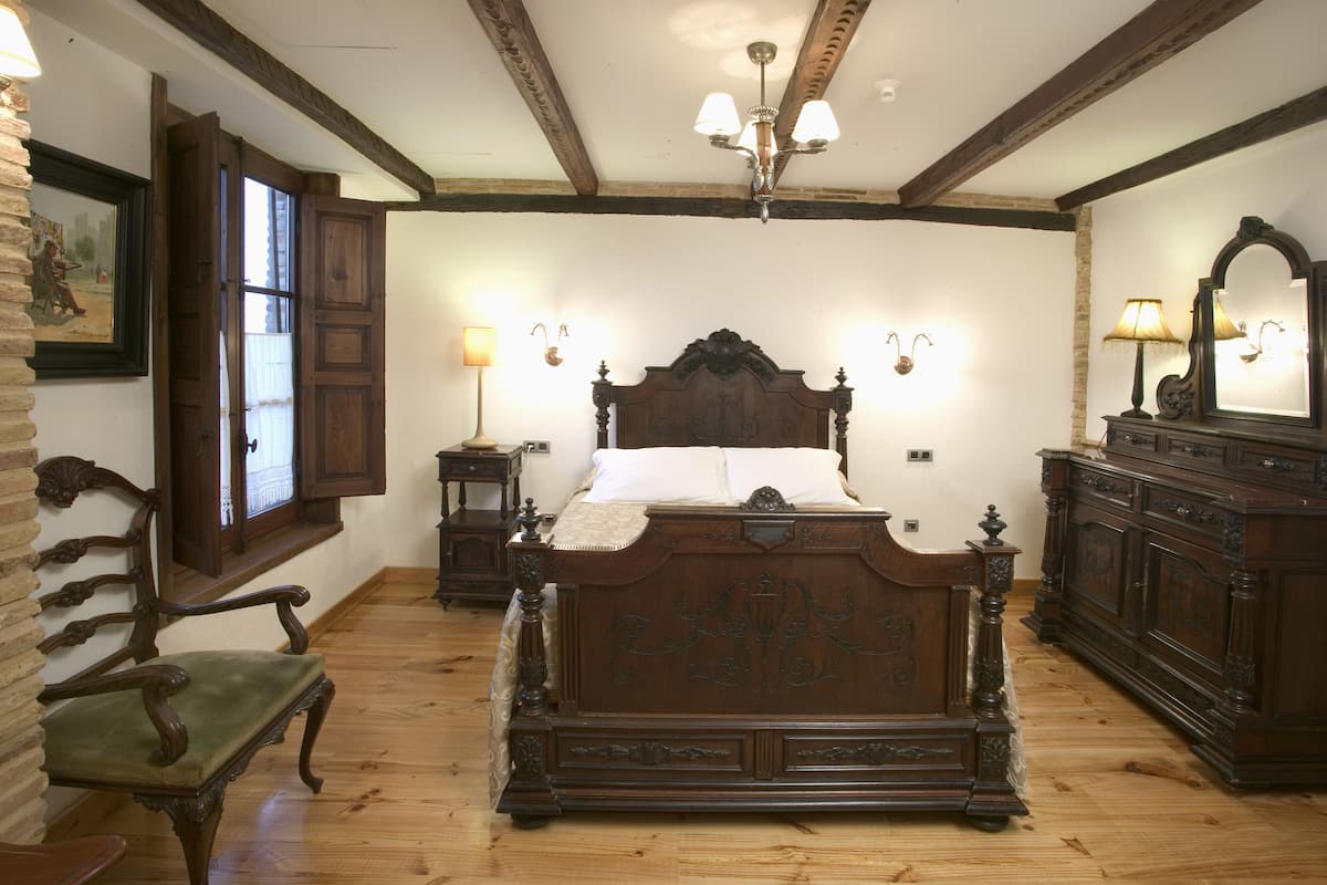A traditional bedroom with a wooden bed, a chair, and a dresser.