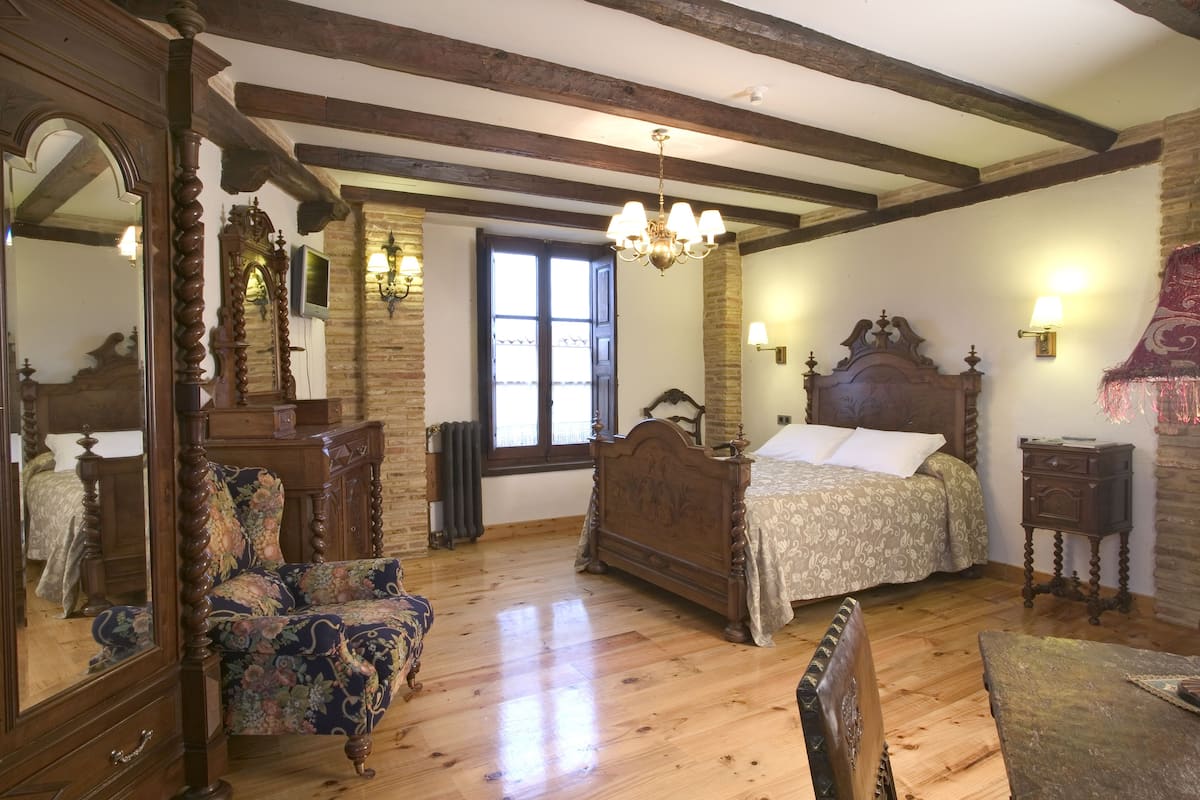 A bedroom with a wooden bed, a chair, a dresser, and a mirror.