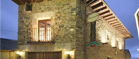 A stone building with a wooden balcony and a sign indicating it is a restaurant.