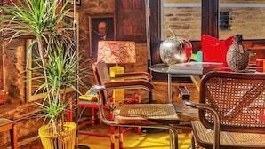 A cozy room with a wooden wall, a potted plant, a vintage lamp, a red chair, a metal table, and a pineapple decoration.