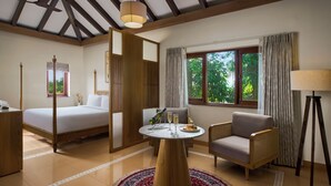 A hotel room with a bed, a round table with two glasses and a plate of food, a chair, a lamp, and a window with curtains. - Mercure Goa Devaaya Resort - An Accor Hotels Brand (Panaji)