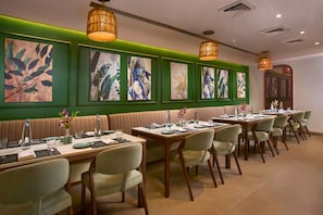 A restaurant with booths, tables, and chairs, with artwork on the walls and pendant lighting. - Mercure Goa Devaaya Resort - An Accor Hotels Brand (Panaji)