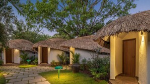 A courtyard with thatched-roof huts, stone pathways, and lush greenery. - Mercure Goa Devaaya Resort - An Accor Hotels Brand (Panaji)