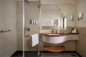 A modern bathroom with a glass shower enclosure, a sink with a wooden countertop, and a mirror above the sink.