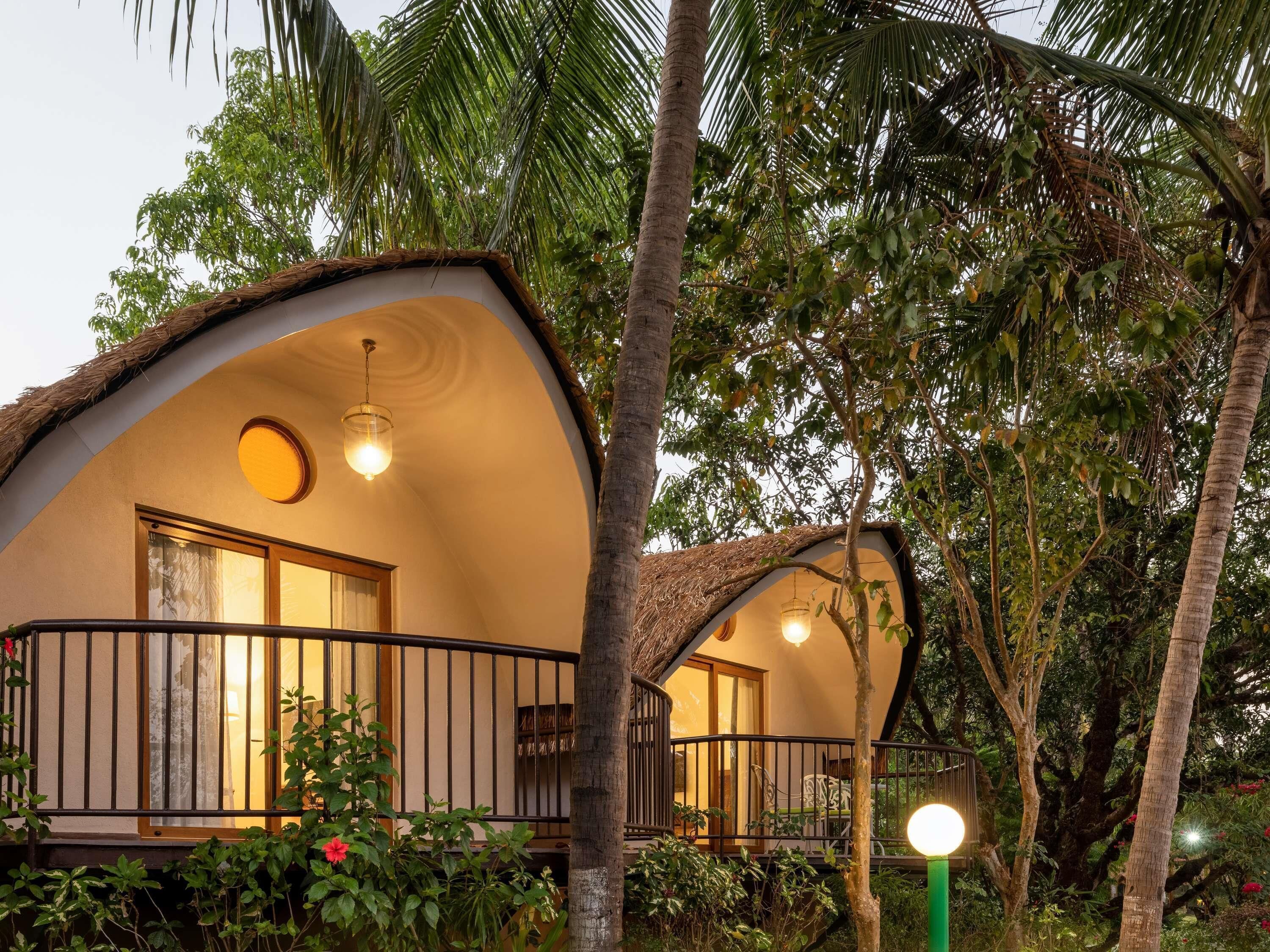 A bungalow with a curved roof, a balcony with a railing, and a hanging light fixture.