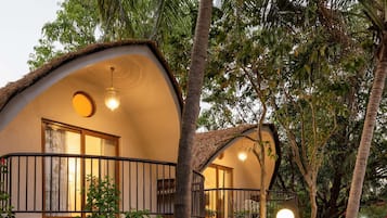 A bungalow with a curved roof, a balcony with a railing, and a hanging light fixture.