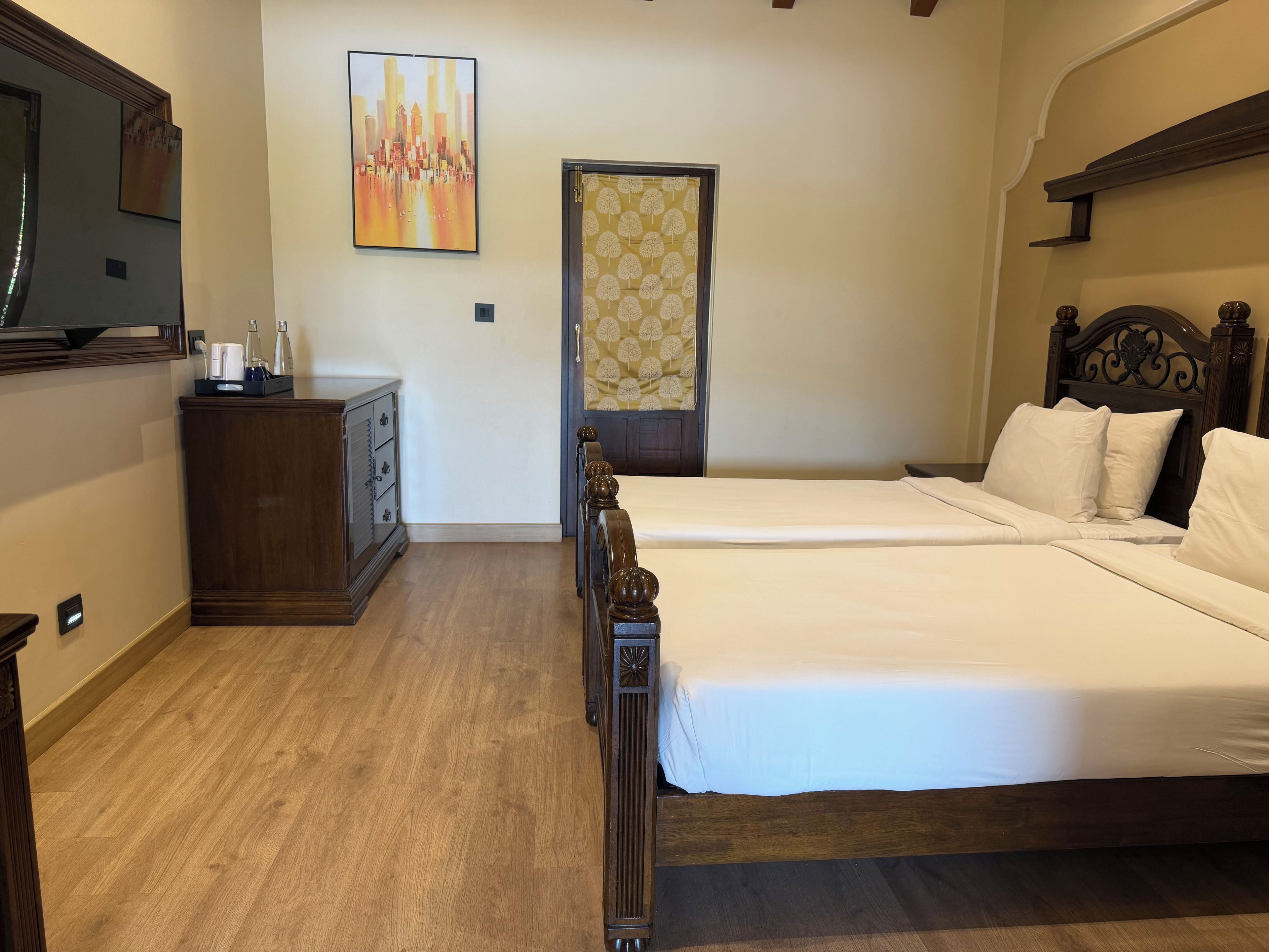 A hotel room with a wooden bed, a dresser, a mirror, and a painting on the wall.
