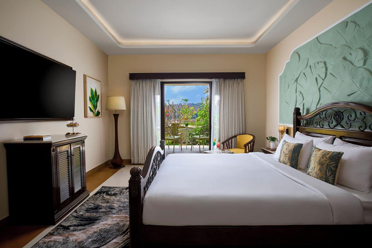 Ein Hotelzimmer mit einem groĂen Bett, einem Fernseher, einem Schreibtisch und Blick ins Freie.
