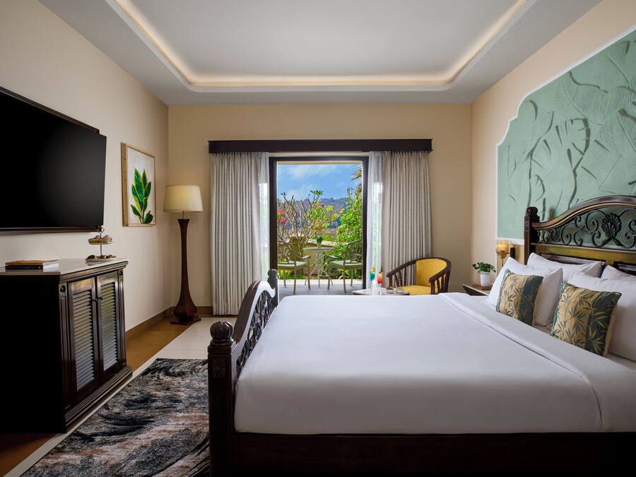 A hotel room with a large bed, a television, a desk, and a view of the outdoors.