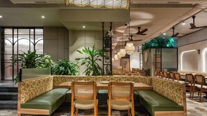 A restaurant with a central seating area featuring a curved bench and wooden chairs, surrounded by tables and chairs.