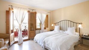 A hotel room with a large bed, a bedside table with a lamp, and a view of the balcony. - Rusticae Rincón de Traspalacio (Robledo de Chavela)