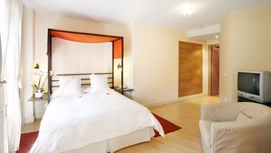 A hotel room with a large bed, a TV, a chair, and a wardrobe. - Rusticae Rincón de Traspalacio (Robledo de Chavela)