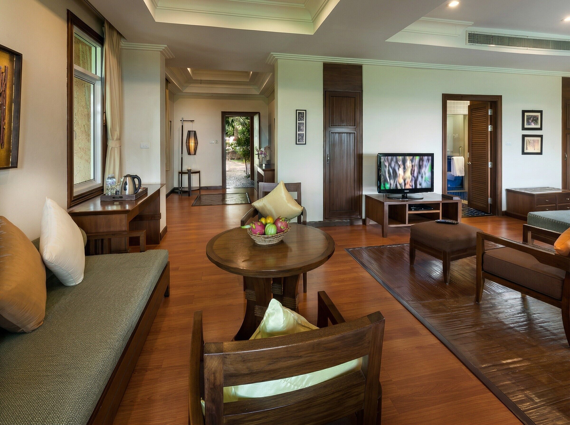 A spacious living room with a sofa, armchair, coffee table, and TV.