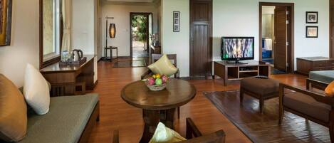 A spacious living room with a sofa, armchair, coffee table, and TV.
