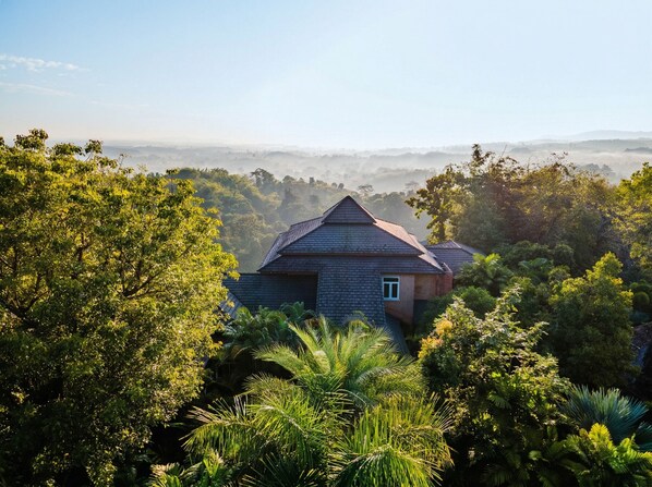 Una casa rodeada de vegetación exuberante y un paisaje brumoso.