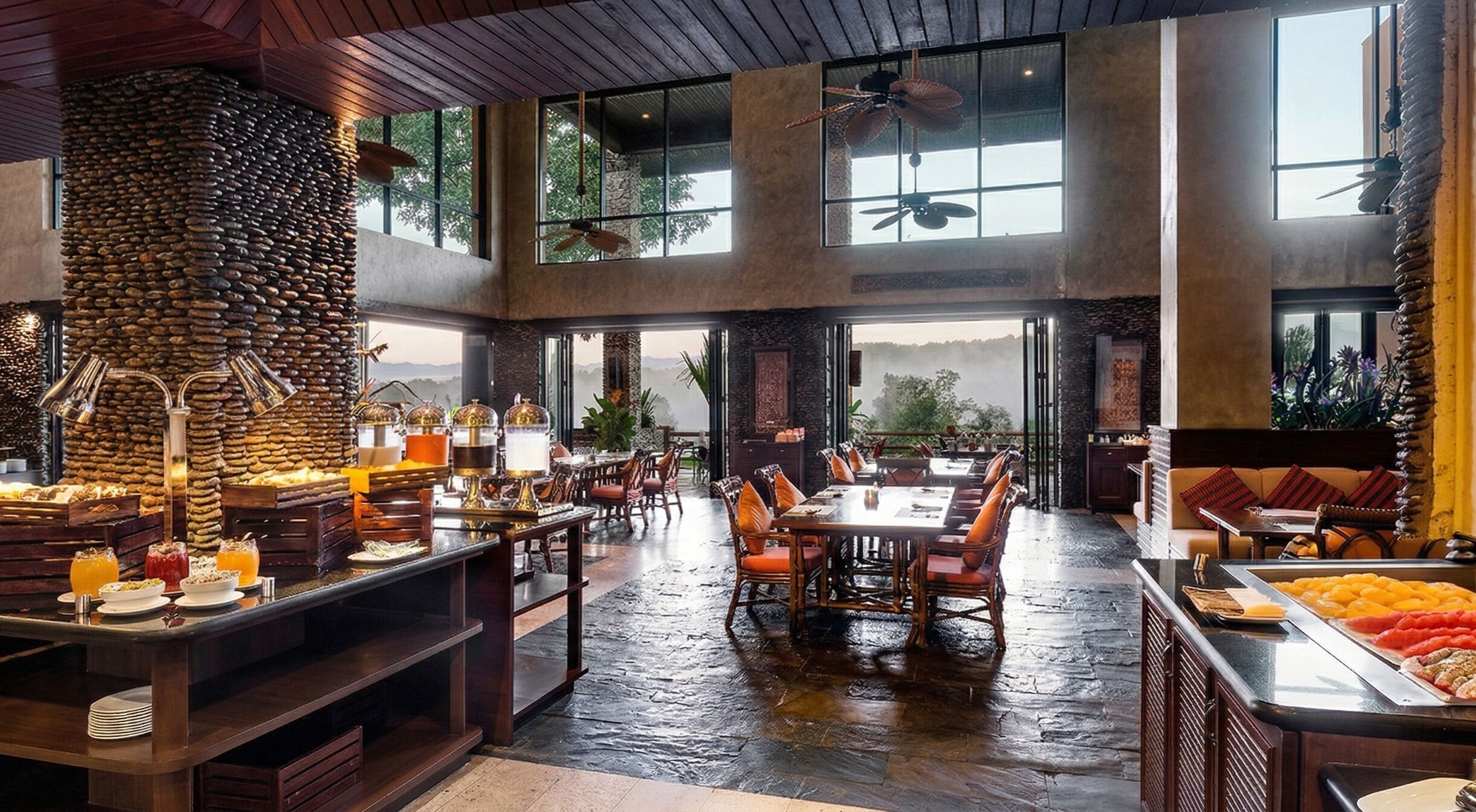 A spacious dining area with high ceilings, large windows, and a stone wall centerpiece.