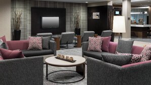 Ein moderner Loungebereich mit Sofas, einem Couchtisch und einem an der Wand befestigten Flachbildfernseher.