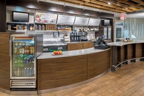 A modern coffee shop with a refrigerated display case, a coffee machine, and a menu board. - Courtyard by Marriott Austin Parmer/Tech Ridge (Austin)