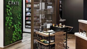 Ein modernes Geschäftsisori mit einer grünen Mooswand mit dem Schriftzug „CRATE“, Holzböden voller Produkte und einem Metallabtrennung mit der Beschriftung „CRATE“.