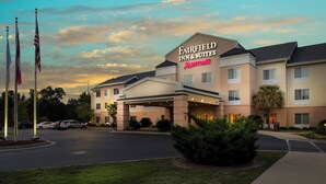 Un hotel Fairfield Inn & Suites Marriott con entrada cubierta, varias banderas y un estacionamiento.