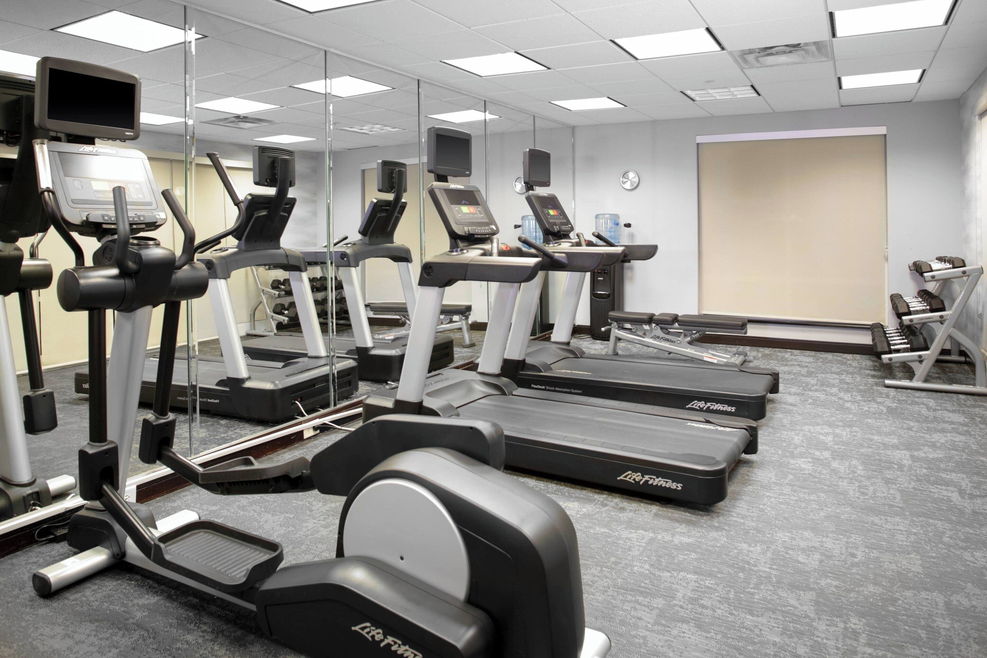 Un gimnasio con cintas de correr, elípticas y máquinas de pesas.